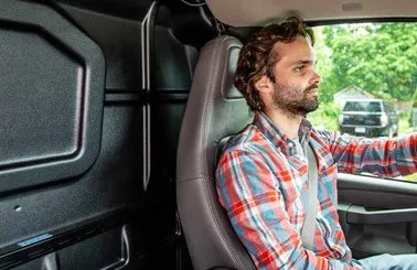 a man driving a work van with an Adrian Steel partition dividing the cab side from the cargo side of the van