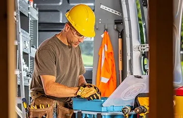 a man wearing a safety helmet inside a van looking into an Adrian Steel small portable parts case