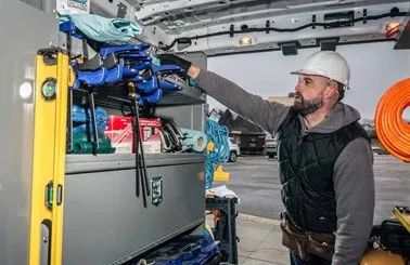 man organizing materials and work tools on an Adrian Steel shelf unit inside a van