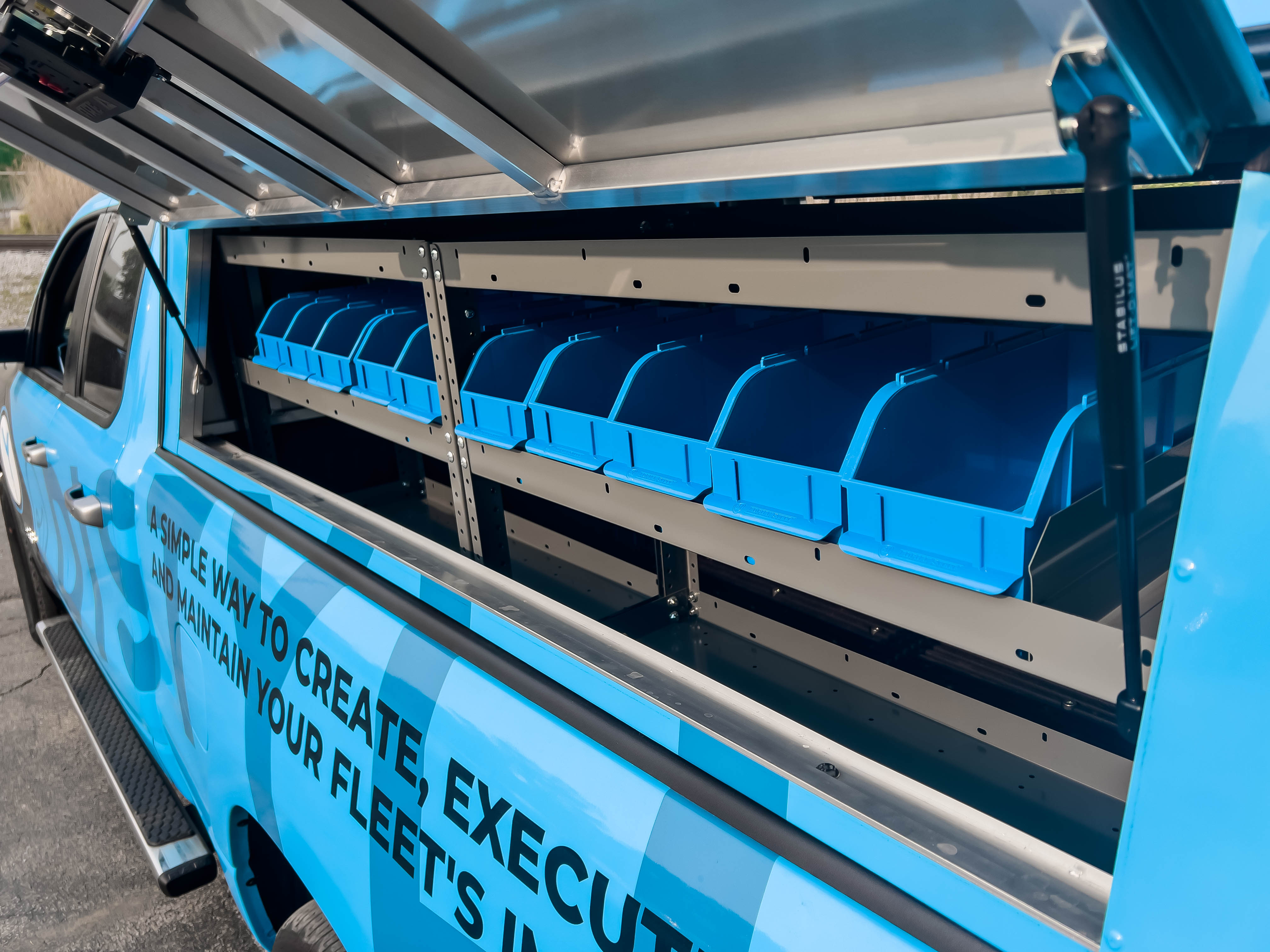exterior view of two shelves containing several portable bins in a pickup upfitted with an Adrian Steel Electrician package