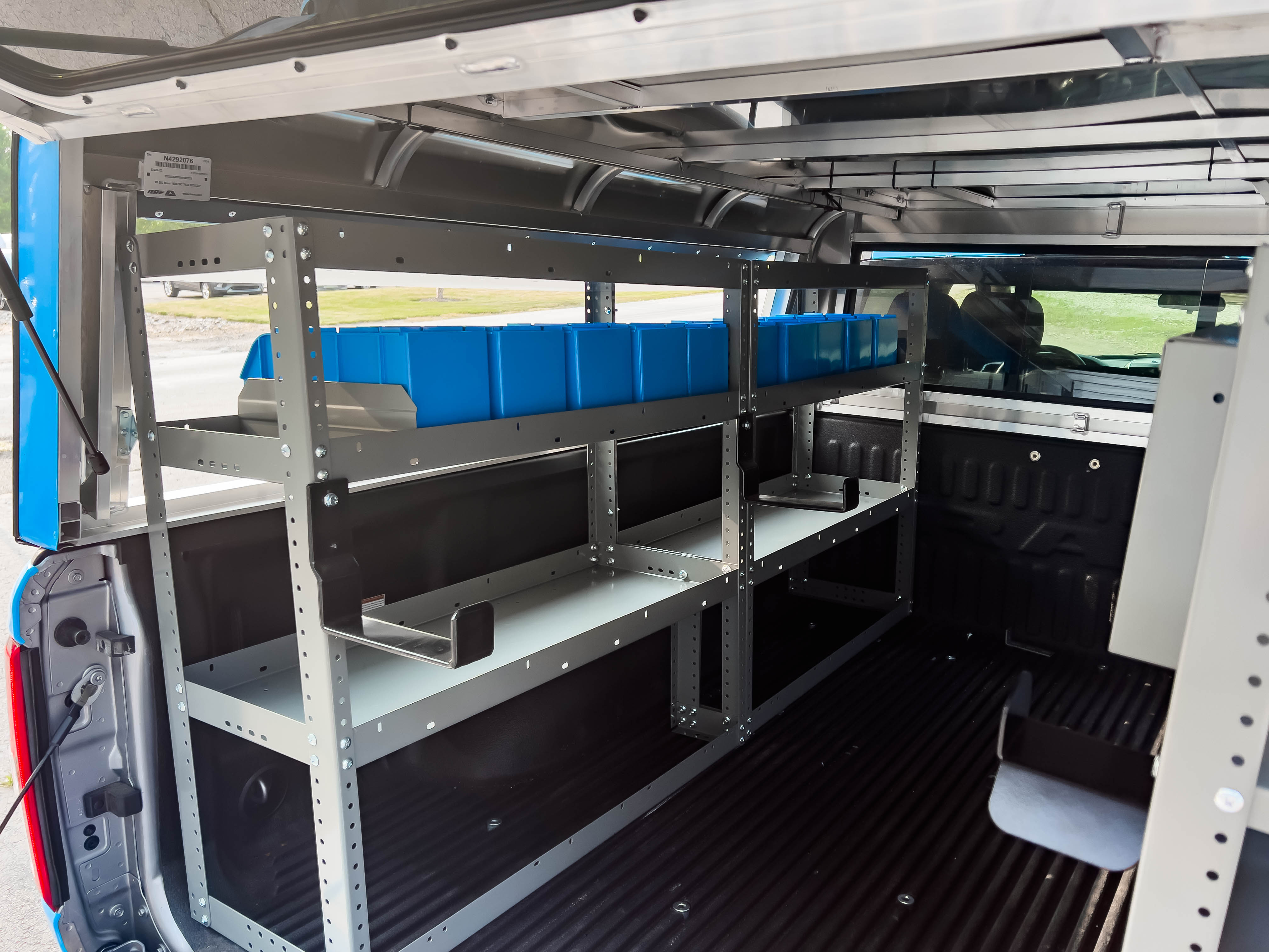 two shelves filled with portable bins in a pickup upfitted with an Adrian Steel Electrician storage package