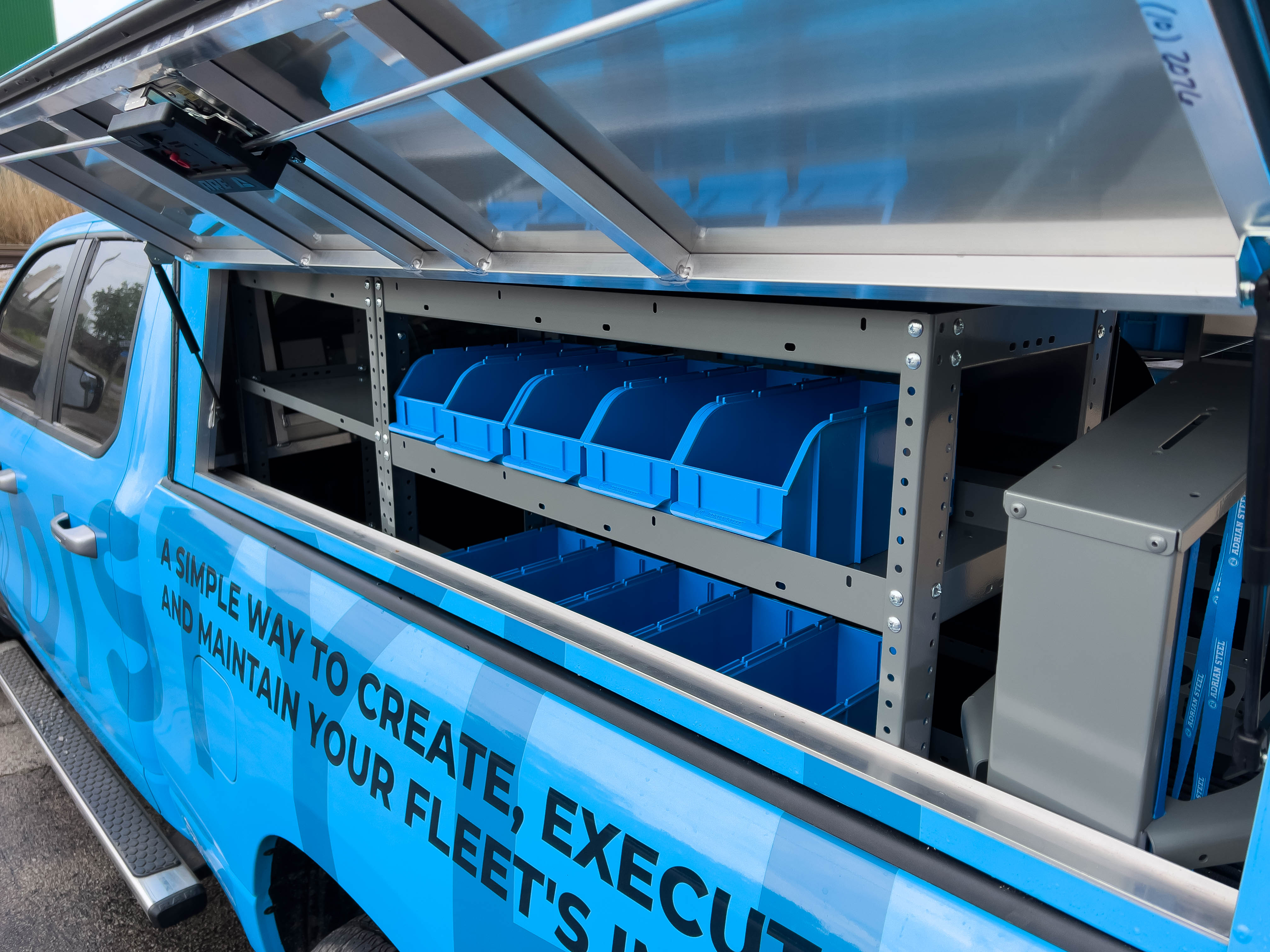 exterior view of two shelves containing several portable bins in a pickup upfitted with an Adrian Steel HVAC package