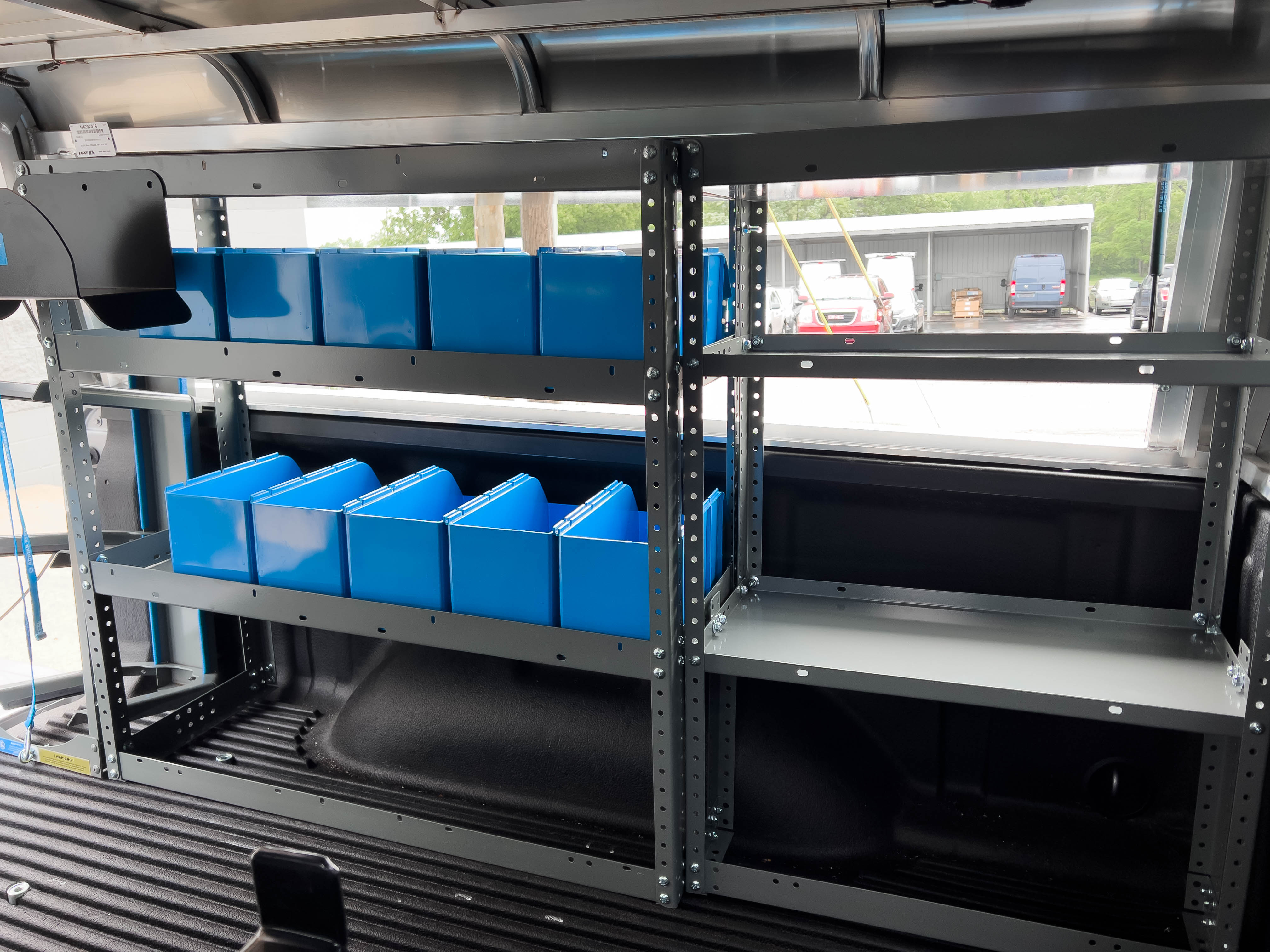 a couple of shelves containing several portable bins in a pickup upfitted with an Adrian Steel HVAC/Mechanical truck package