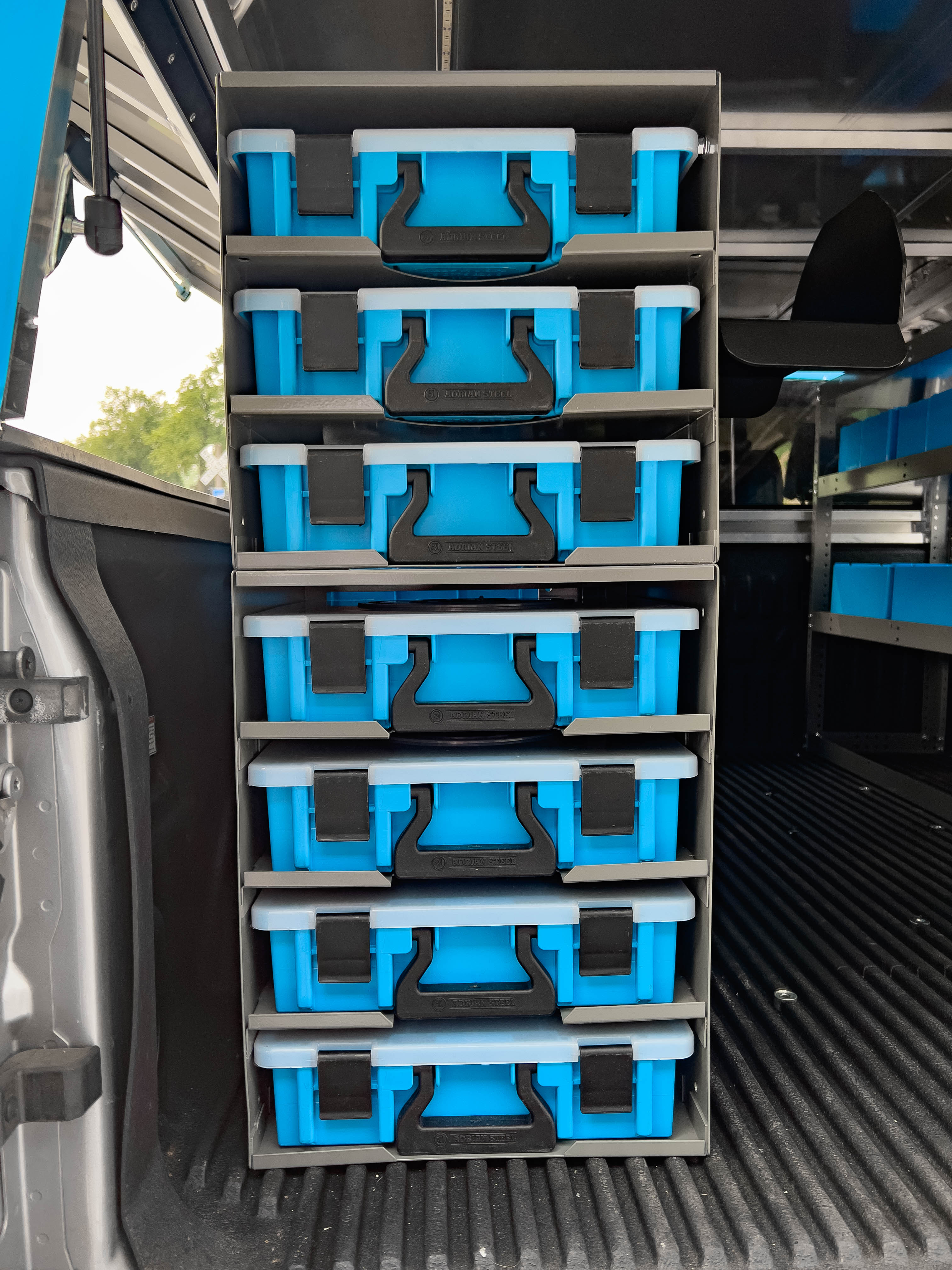 a case holder containing 7 portable parts cases in a pickup upfitted with an Adrian Steel plumber storage package