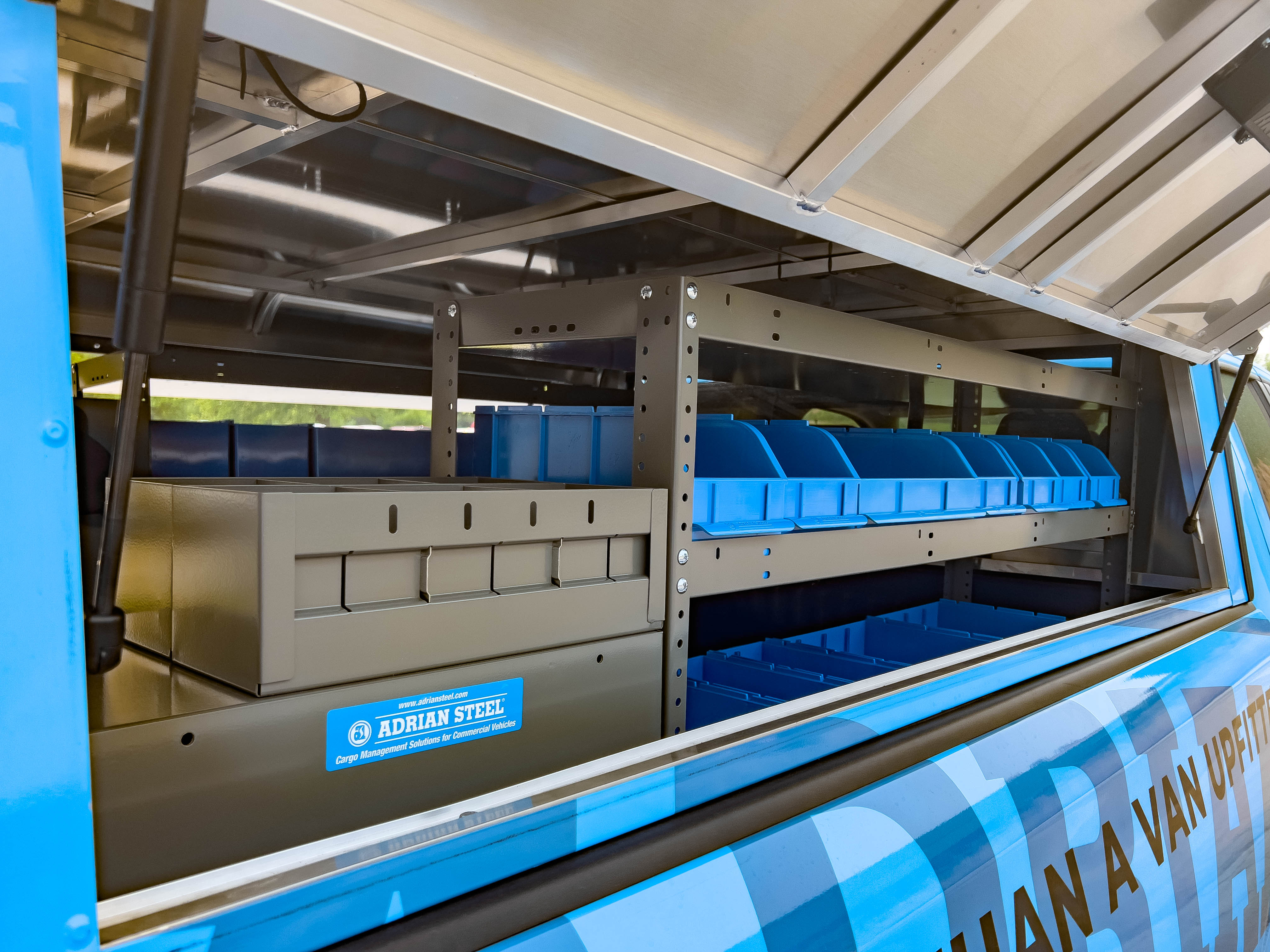 exterior view of a shelf full of portable bins next to a cabinet in a pickup upfitted with an Adrian Steel plumber package