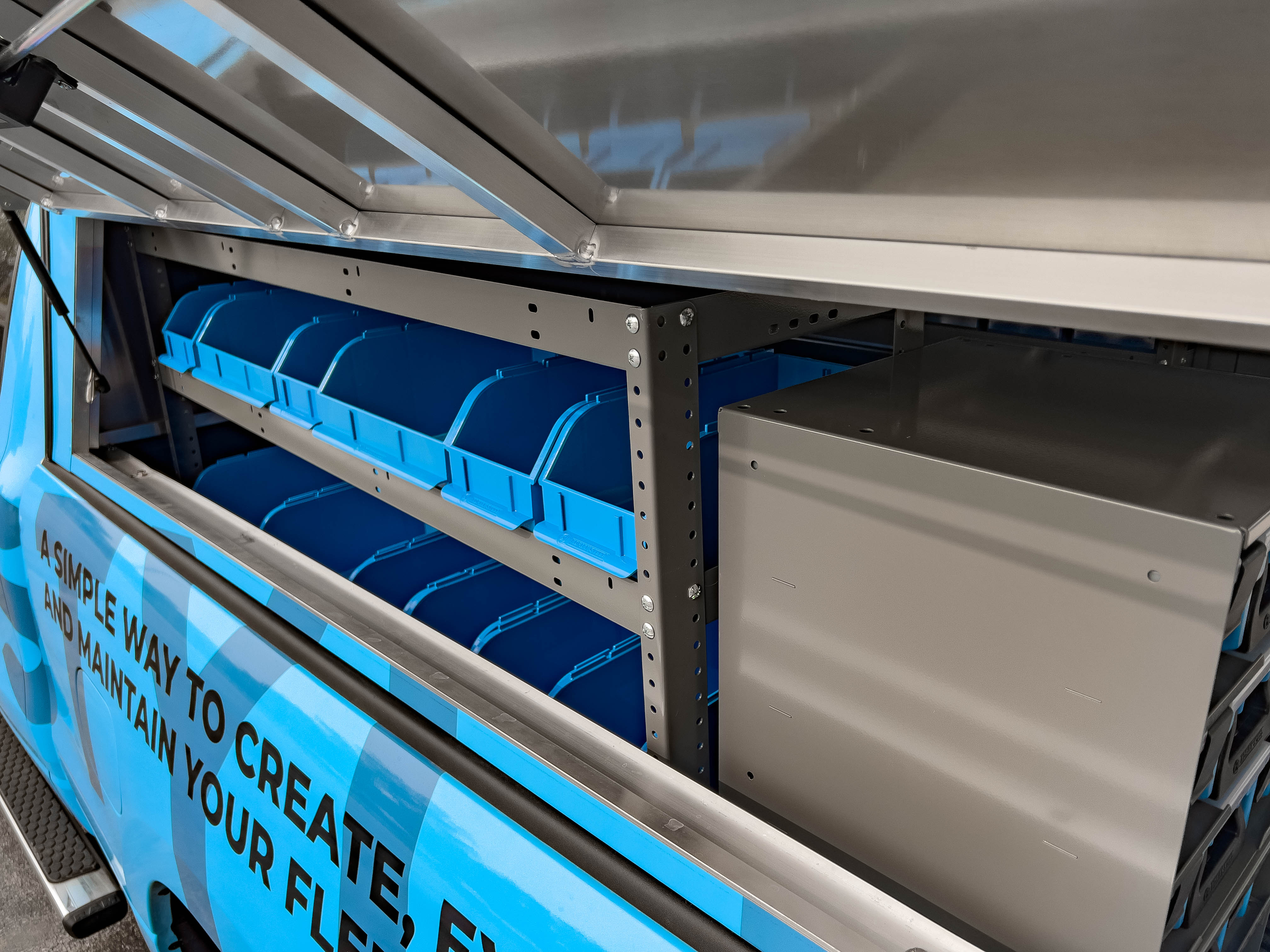 exterior view of shelf full of portable bins next to a case holder in a pickup upfitted with an Adrian Steel plumber package