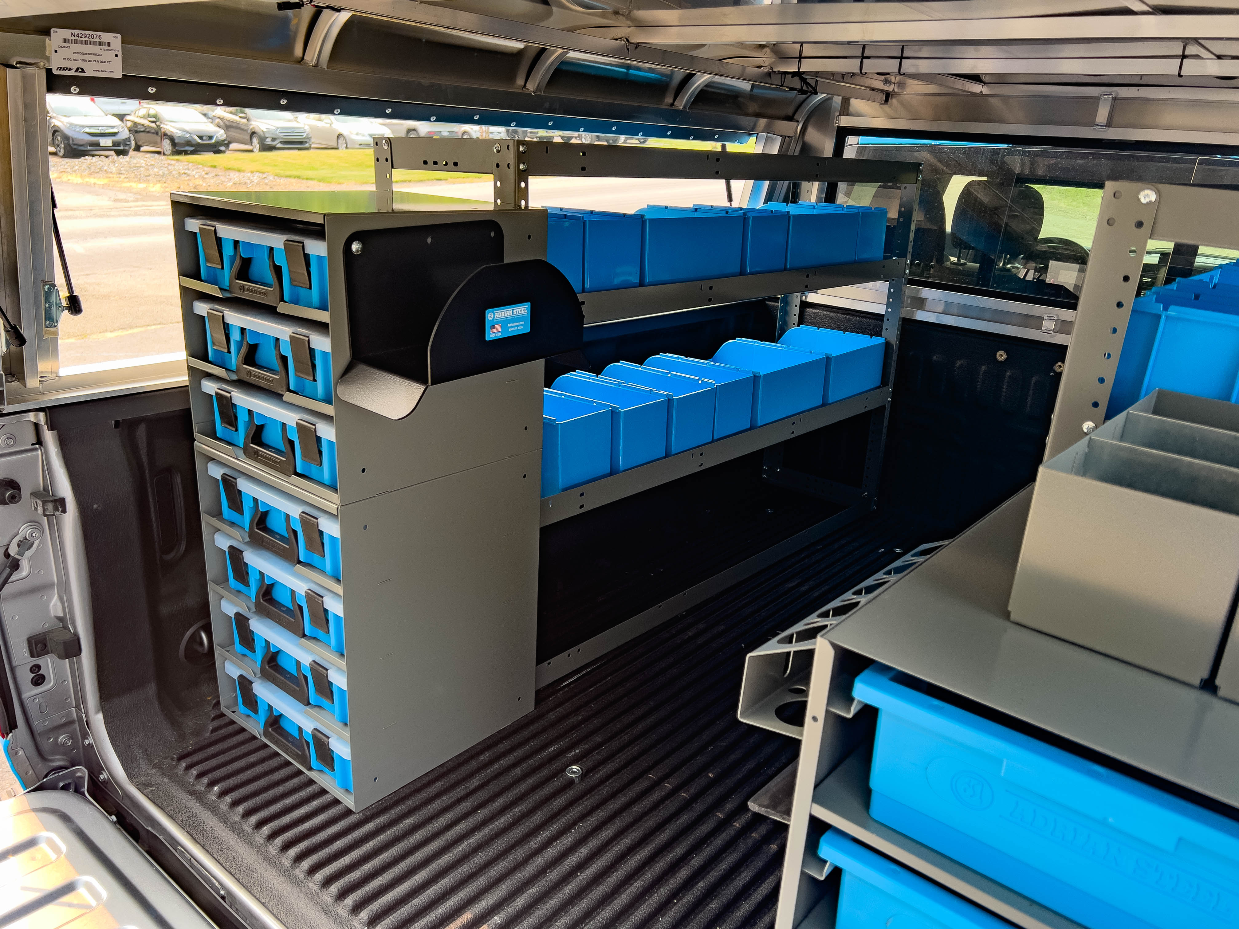 a shelf full of portable bins next to a portable parts case holder in a pickup upfitted with an Adrian Steel plumber package
