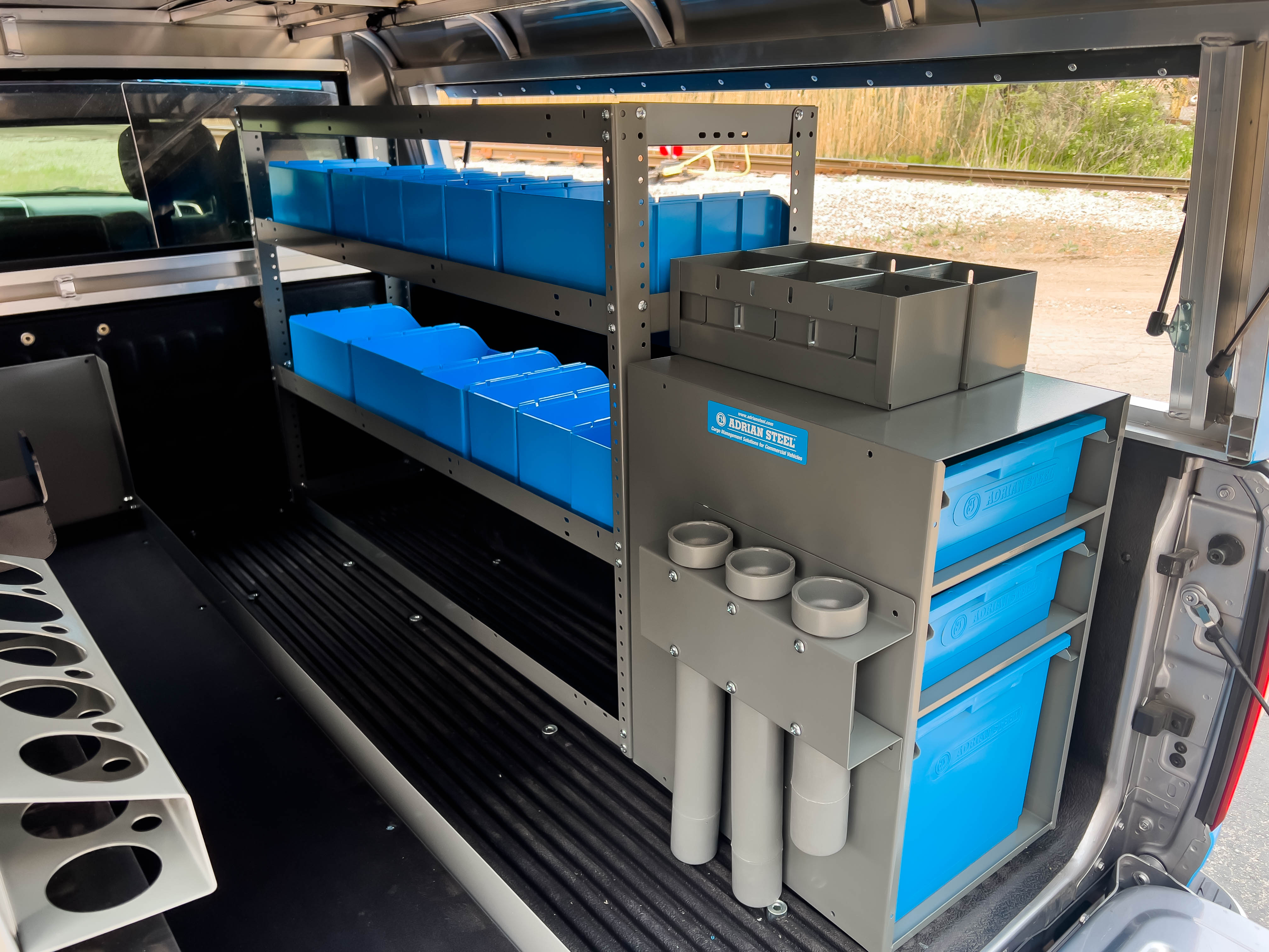 two shelves filled with portable bins next to a cabinet in a pickup upfitted with an Adrian Steel Security Contractor package