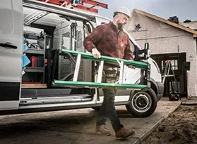 Nuilder unloading a small ladder from his upfitted work van.