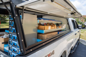 a white truck with a truck bed shelving system installed filled with work supplies