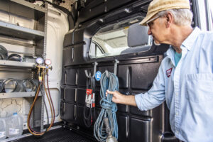 Man lifting a rope hanging off of a van partition.