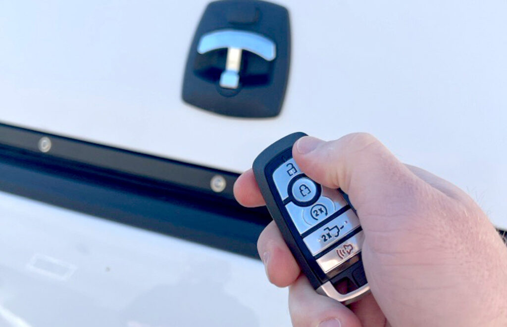 holding keyless entry car fob above a truck topper e-lock system to unlock it