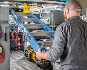 A workers sliding the ladder out of his van where it's secured in an internal ladder storage solution