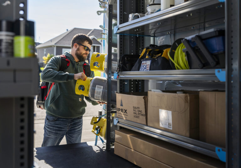 Technician getting tools out of the back of a van organized with a cargo management system