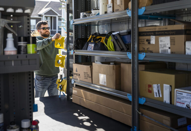 Worker loading spools onto an upfitted van with shelving storage